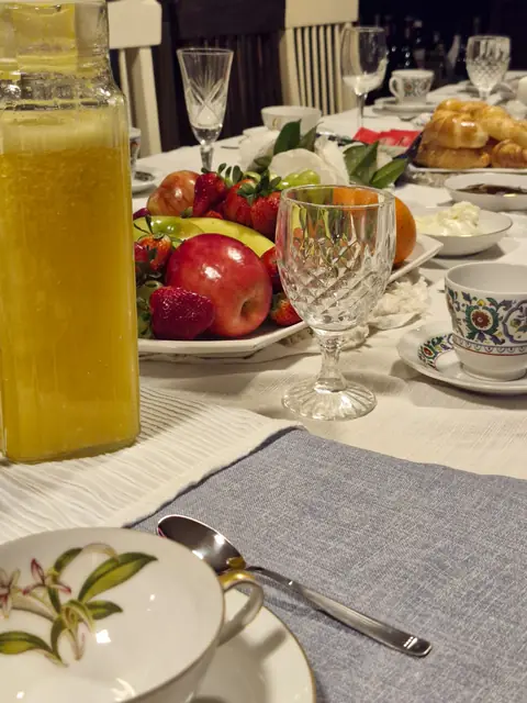 Mesa de desayuno con frutas, jugo exprimido y facturas
