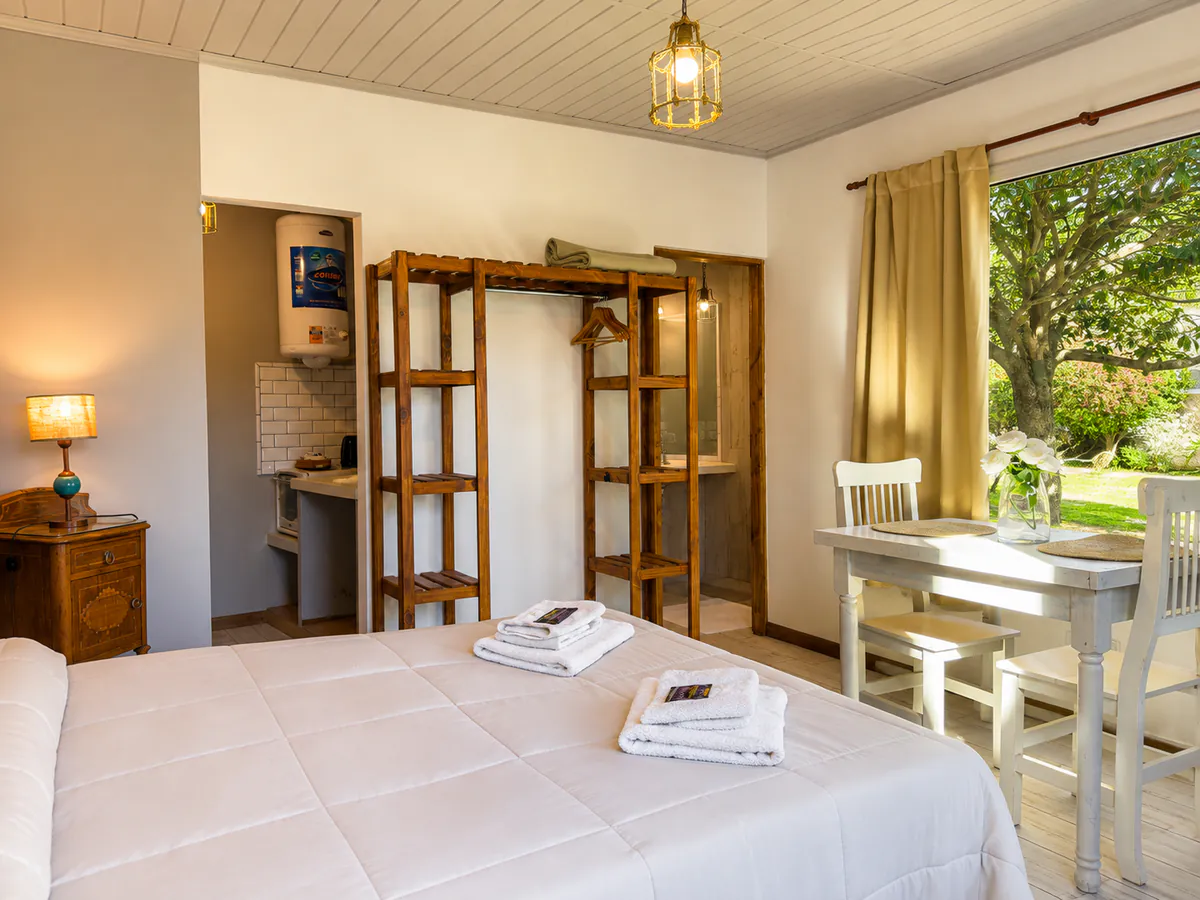 Ambiente de la Suite 13 con cama matrimonial y ventanal al parque